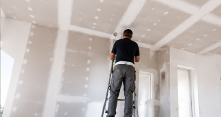 Travaux de plâtrerie et placo Plaquiste réalisant les finitions d'un plafond en plaques de plâtre dans une maison